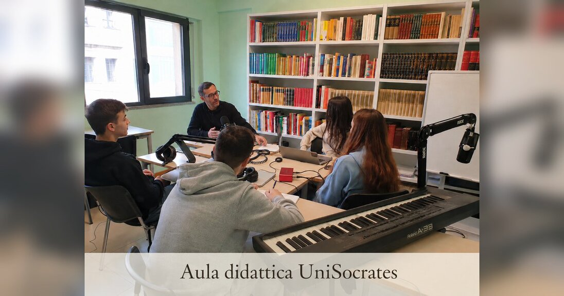 Aula didattica UniSocrates per lezioni, tutoraggio e attività formative Aula didattica UniSocrates con studenti, studentesse e docente durante un’attività formativa, con libri, strumenti musicali e attrezzature per lezioni online e in presenza.